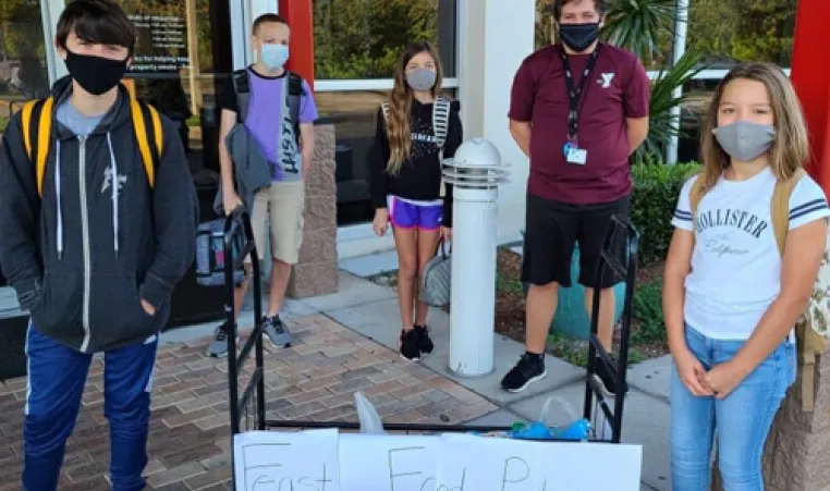 Middle school kids wearing masks collecting food