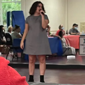 A MASH program participant performing karaoke indoors, in front of friends. The program, MASH, is for adults with physical, cognitive and developmental disabilities, including people who have autism.